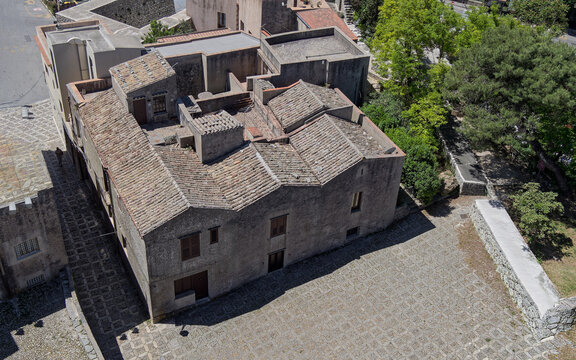 High-angle aerial-style view of a traditional stone building with a inner courtyard and tiled roof next to Piazza Matrice in Erice, Sicily.
