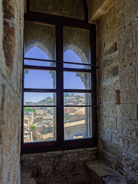 View looking out a Gothic bifora window frame from inside King Frederick's Tower toward the medieval townscape of Erice, Sicily.