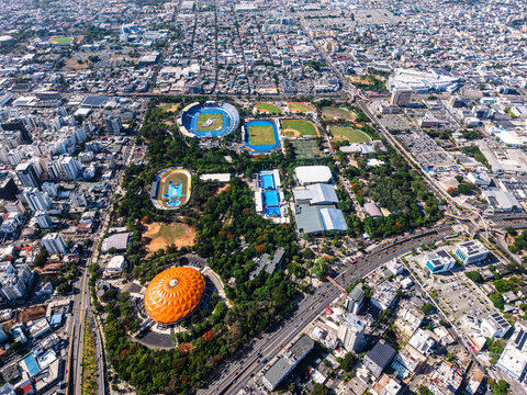Santo Domingo, Dominican Republic - 24 July 2026: Aerial view of Centro Olimpico Juan Pablo Duarte featuring sports stadiums, athletic tracks, and lush green spaces surrounded by the urban cityscape.