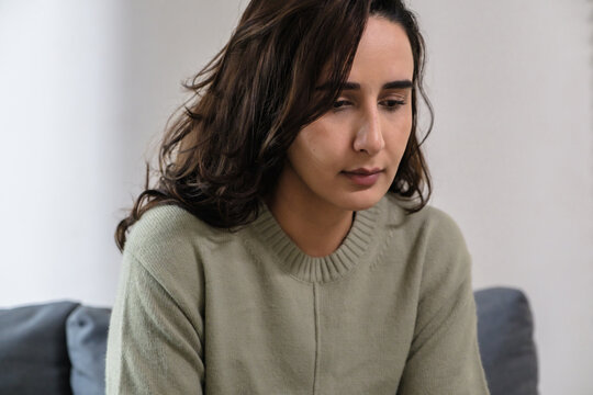 Sad anxious woman feeling stress and depression while sitting alone on sofa, suffering emotional problem and mental frustration at home