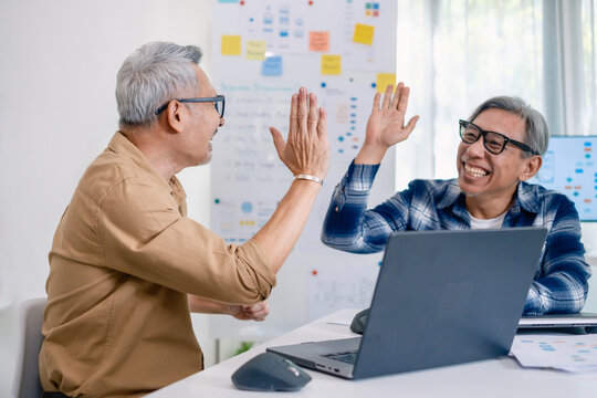 Senior developer team celebrates success in software collaboration and coding at a modern computer workstation