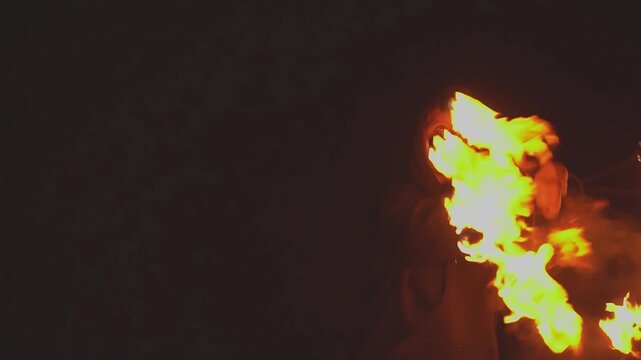 Night show. Black hood on head. Black hoodie. Fire show. Fire fan. Slow motion video. High quality 4k footage
