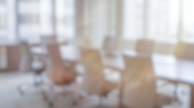 abstract out of focus blurred corporate boardroom conference room interior table row of ergonomic office chairs bright window light background