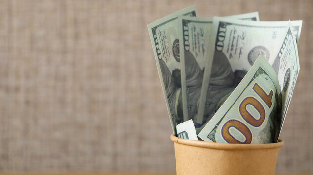 Money bills arranged in a small container placed on a table with a simple background