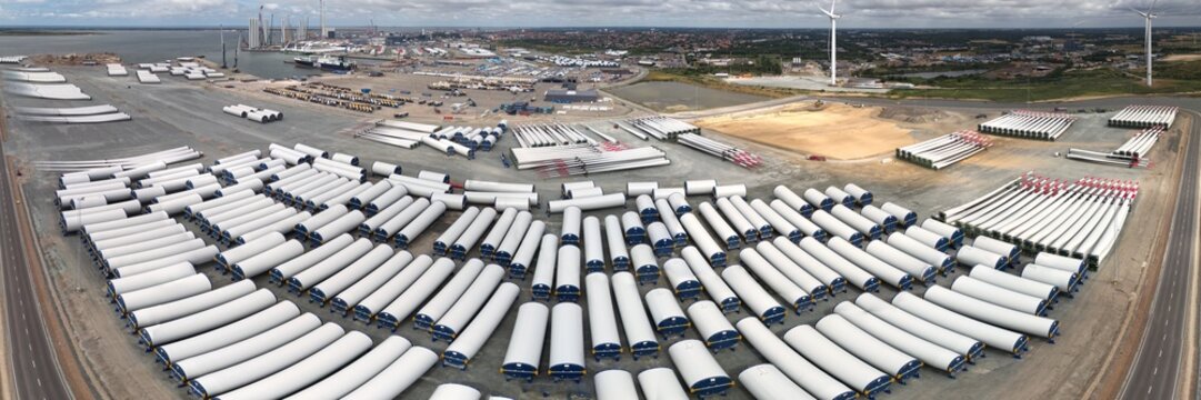 Esbjerg, Denmark - 24 July 2026: Aerial view of Esbjerg harbour with rows of wind turbine blades and shafts stored for transport, alongside a DFDS ship and industrial construction.