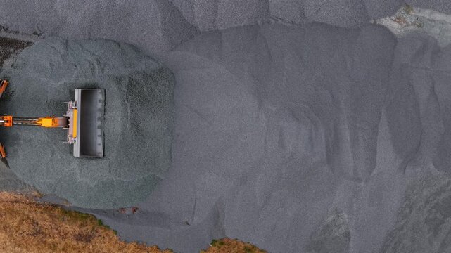 Road grader construction site. Orange telehandler near gravel aggregate pile with drone top view and industrial texture. Civil engineering machinery at highway maintenance materials depot