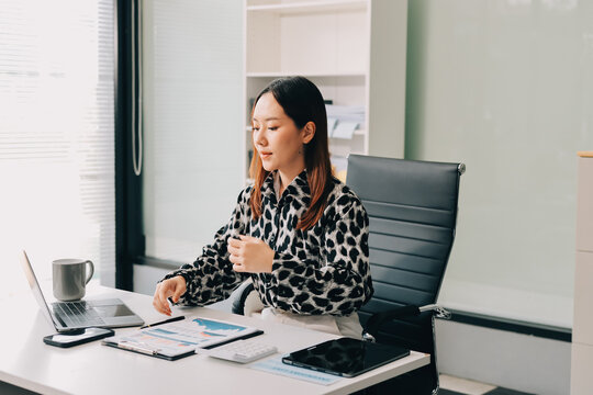 Office Discomfort: A female office worker in a red shirt experiences neck pain while working on her laptop, surrounded by office supplies and a calculator, indicating a stressful work environment.