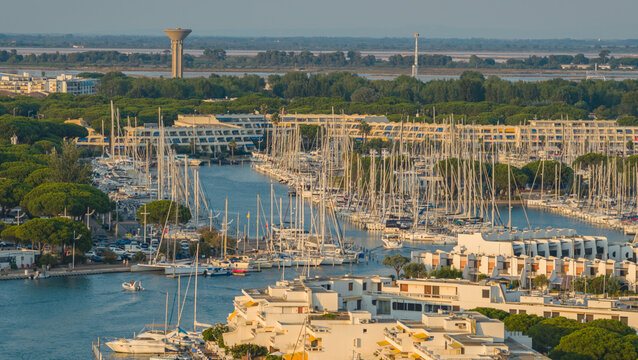 Le Grau-du-Roi, France - 18 July 2026: Aerial view of Port Camargue, a large marina with hundreds of sailing yachts, modern waterfront buildings, and pine trees.