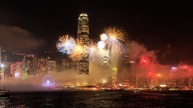Spectacular fireworks exploding over a vibrant Hong Kong cityscape at night.