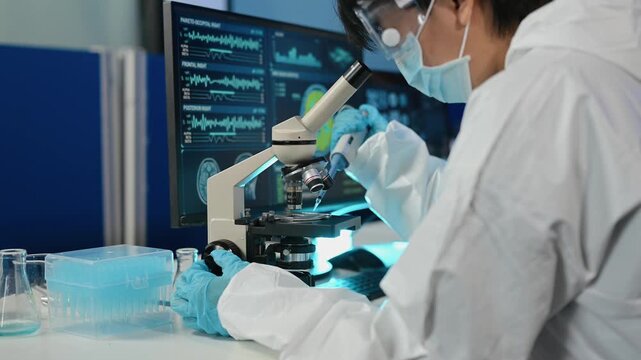 Scientist in protective suit analyzes neurological data and biological samples using a modern microscope in a high-tech laboratory.