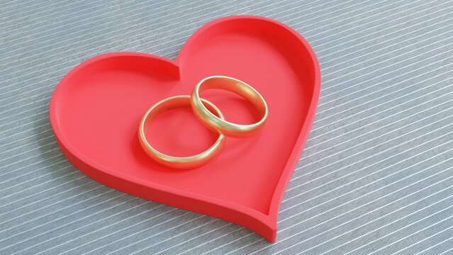 Two gold wedding rings and a red heart on a gray background, love and lifelong commitment concept