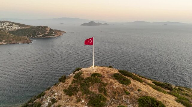 Aerial Orbit Turkish Flag on Hilltop Bodrum Coastline Sunset