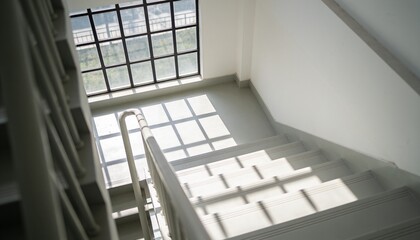 Fototapeta premium Showing flight of stairs descending at upper landing, featuring metal handrail and grid shadows