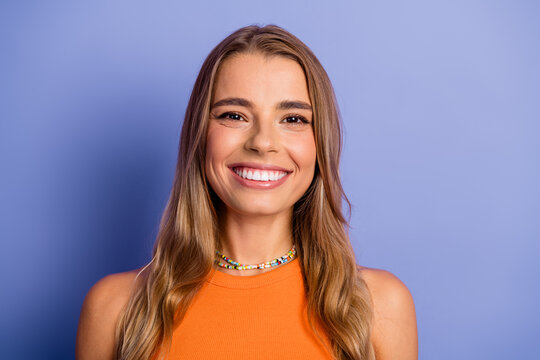 Young chic gorgeous blonde woman smiling in orange singlet against purple background ready for fashion lifestyle advertising and shopping promotion