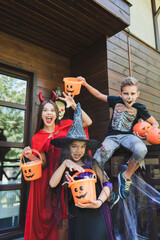 Fototapeta premium Family having Halloween fun trick-or-treating by their cottage