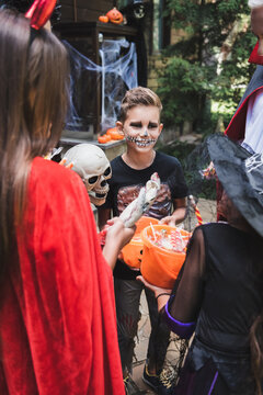 Family enjoys Halloween fun while trick or treating near decorated cottage