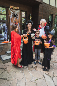 Happy family enjoying Halloween trick or treating at a festive cottage house