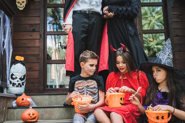 Fototapeta premium Joyful family celebrating Halloween while trick or treating by a cozy cottage