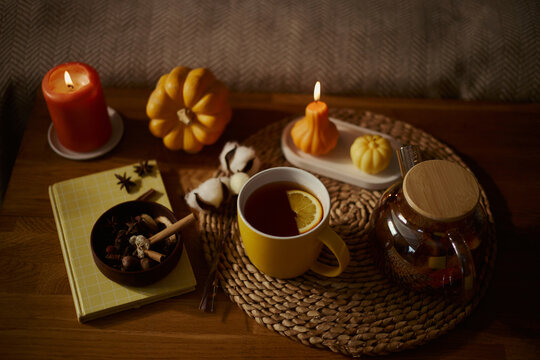 Autumn flat lay with hot tea, pumpkin candles, and notebook on wooden table, representing seasonal wellness. Image ideal for lifestyle blogs and fall marketing campaigns, high angle view
