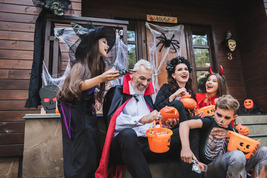 Happy family in costumes enjoys treats by a decorated house