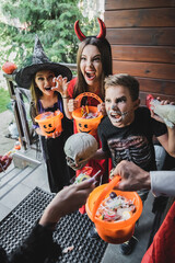 Fototapeta premium Family enjoys Halloween fun while trick or treating near their decorated cottage