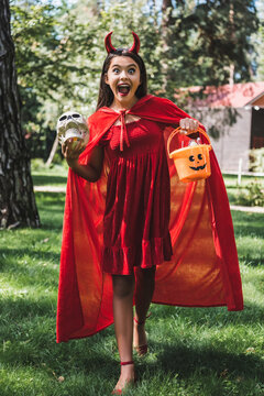 Cute kid excited for Halloween in a devil costume near spooky decorated house