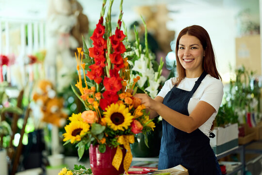 Smiling Female Florist Arranging Bright Sunflower and Gladiolus Bouquet in Flower Shop Interior