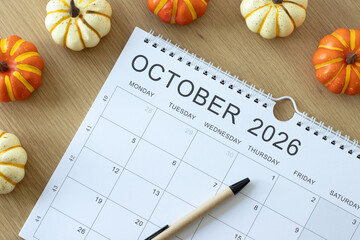 October 2026 calendar month with pumpkin decoration on a wooden background. Top view. © Marinela