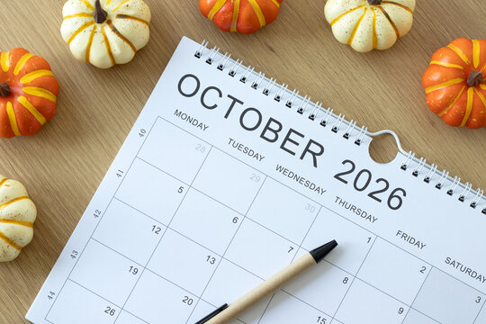 October 2026 calendar month with pumpkin decoration on a wooden background. Top view.