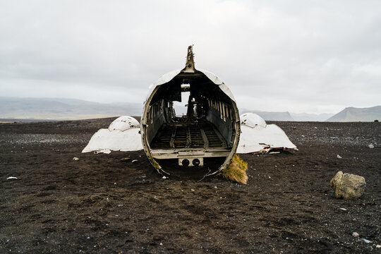 Abandoned airplane wreckage on black sandy terrain
