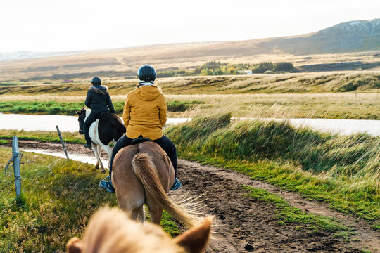 Two riders enjoying horseback trail riding along a river