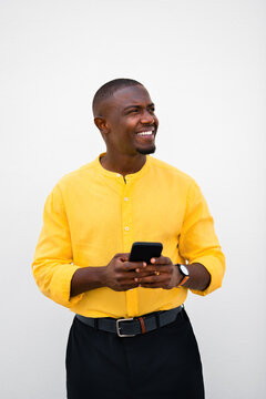 African american man, businessman holding phone, chatting and looking aside with smiling expression in casual, isolated vertical business portrait in studio during a busy office weekday