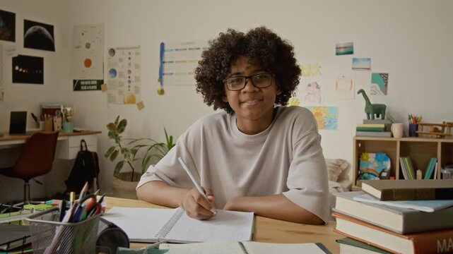 Portrait of African American teenager sitting at desk, looking into camera. Perfect for online learning platforms, tutoring services, and educational marketing campaigns