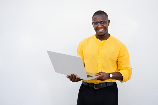 African american man, businessman holding open laptop, smiling expression facing camera directly in casual isolated studio business portrait with copy space. Cheerful young consultant showing computer