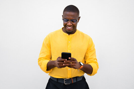 African american man, businessman chatting and texting on phone, casual smartphone device, smiling with messaging in isolated business studio, checking notifications happily