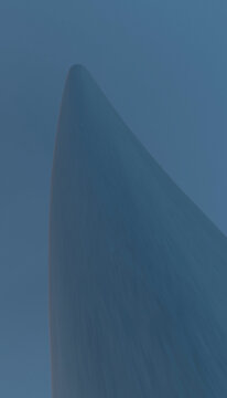 Low angle view of a smooth, pointed monument structure against blue