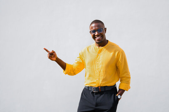 Pointing at copy space, african american man, businessman entrepreneur, cheerful and smiling in casual isolated studio business portrait. Confident young professional presenting new idea