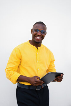 African american man, businessman holding tablet in close casual isolated studio business portrait, vertical shot, cheerful smiling expression. Young marketing specialist browsing content online for