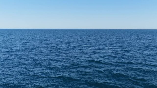 Wide shot of the open Mediterranean Sea under a clear blue sky, filmed off the coast of Moraira, Spain.