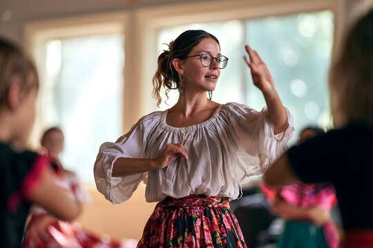 Dance teacher using expressive gestures leading a folk dance class