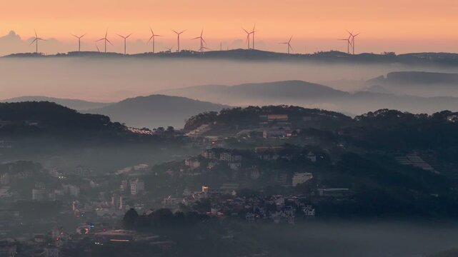 Drone view misty morning on Da Lat city, far away is the line of wind turbines on Cau Dat tea hill, which blanket by fog