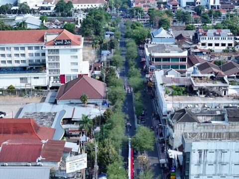 Yogyakarta, Indonesia - 15 August 2026: Aerial view of a street procession in the city center with historic buildings, lush trees, and urban infrastructure.