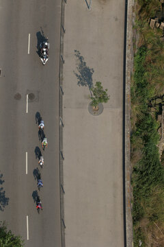 Porto, Portugal - 16 August 2026: View of a group of cyclists riding along a road with a motorcycle escort, captured from a high angle.