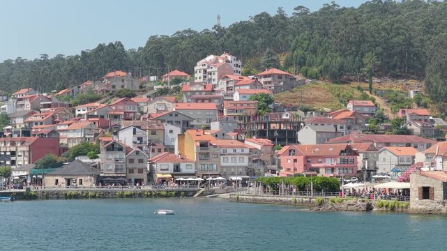 Scenic view of the picturesque coastal village of Combarro, Spain, featuring traditional houses with red-tiled roofs clustered on a hillside by the waterfront.