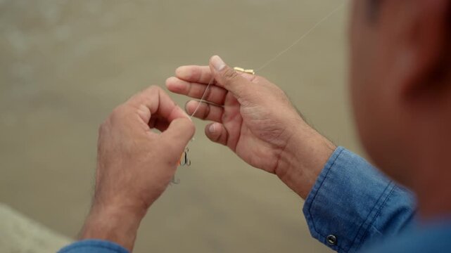 Close-up Senior man preparing fishing gear by the seaside. Retirement lifestyle active aging. Healthy longevity, outdoor recreation, peaceful leisure. Life insurance planning for a secure retirement.
