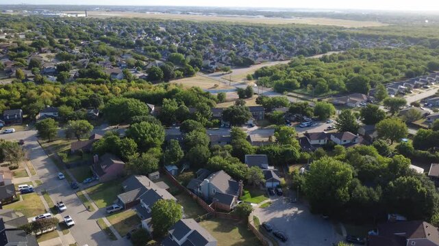 Curved neighborhood cul de-sacs border Southeast Parkway drainage bridge near South Arlington. Two story residential homes overlook lush wooded green belts, driveways, Texas