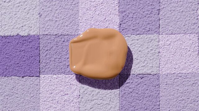 Top-down extreme close-up of a beige foundation blob casting a shadow over a square mosaic background of sifted powder in purple tones | Promotional concept for foundation