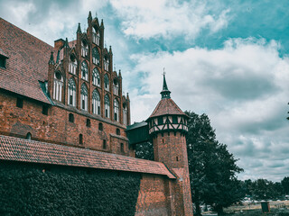 Malbork Castle Architecture with Red Brick Walls and Medieval Turret in Poland Under Cloudy Sky © Marcin
