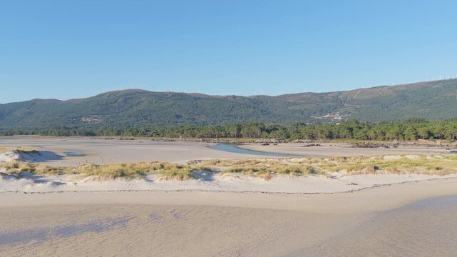 A panoramic view of Praia de Carnota, a vast sandy beach in Carnota, Spain. The scene is tranquil and natural, showcasing the unspoiled beauty of Galicia's coastline with no people visible.