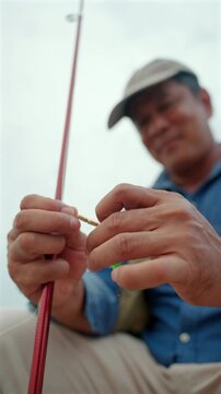 Close-up Senior man preparing fishing gear by the seaside. Retirement lifestyle active aging. Healthy longevity, outdoor recreation, peaceful leisure. Life insurance planning for a secure retirement.
